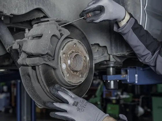 Technician in work gloves servicing a brake rotor and caliper