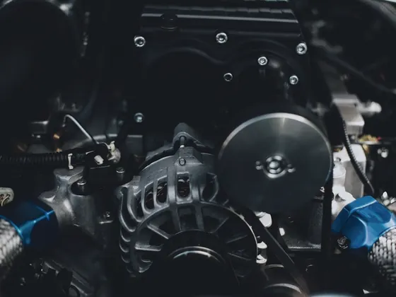 Close-up of an engine bay with alternator, belts and wiring