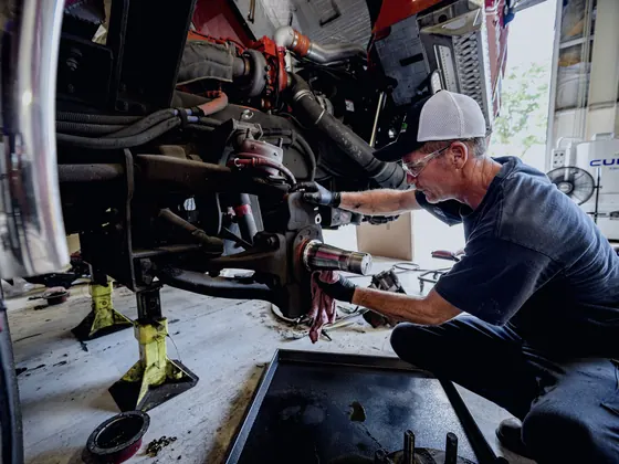 Mechanic repairing a wheel hub and suspension on a raised vehicle