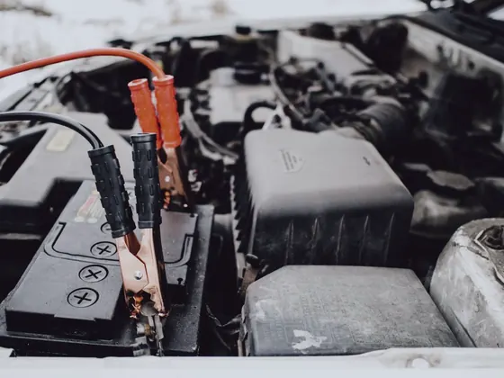 Jumper cables connected to a car battery under the hood