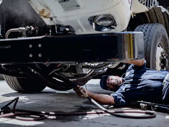 Mechanic lying under a vehicle inspecting the chassis
